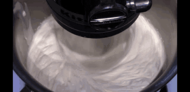 a kitchenaid mixer is making whipped cream in a silver bowl