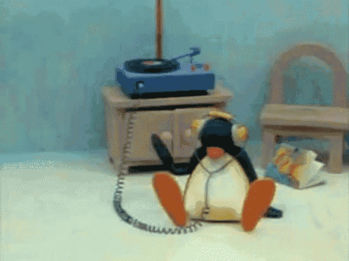 a stuffed penguin wearing headphones is sitting on the floor