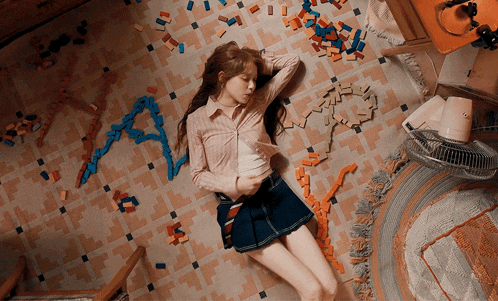 a girl is laying on the floor surrounded by toys