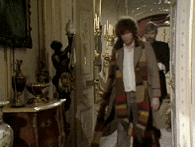 a man in a striped coat is standing in a room