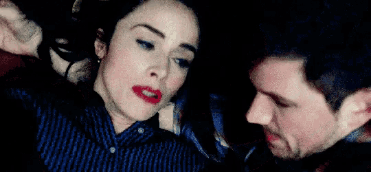 a man and a woman are hugging each other in a dark room . the woman is wearing red lipstick .