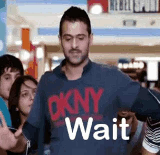 a man wearing an okny wait shirt stands in front of a crowd