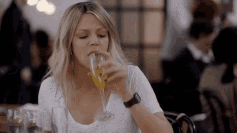 a woman is drinking a glass of wine in a restaurant .