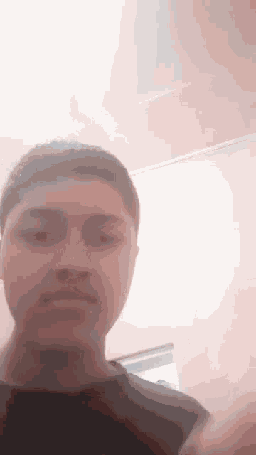 a young man is taking a selfie in a room with a pink wall .