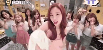 a group of women are standing in a room . one of the women is wearing a pink dress .
