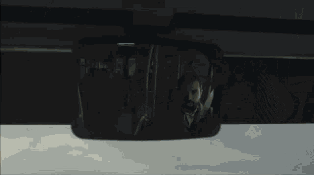 a man is reflected in a rear view mirror of a car