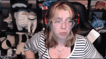 a woman wearing glasses and headphones is sitting in front of stuffed animals .