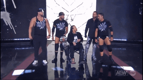 a group of wrestlers are on a stage with a tnt logo on the bottom