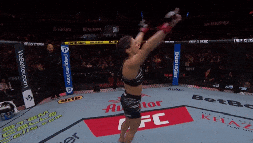 a woman in a ufc ring celebrates her win