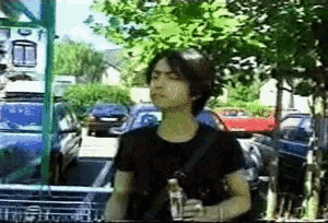 a man in a black shirt is holding a bottle of water in front of a sign that says ' a ' on it