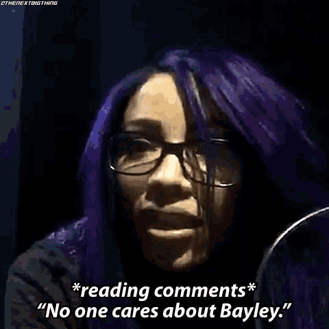 a woman with purple hair and glasses is talking into a microphone and saying reading comments no one cares about bayley