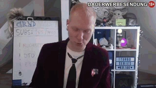 a man in a suit and tie stands in front of a sign that says dauerwerbesendung 18+