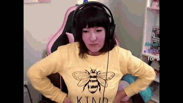a woman wearing headphones and a yellow shirt with a bee on it is sitting in a chair .