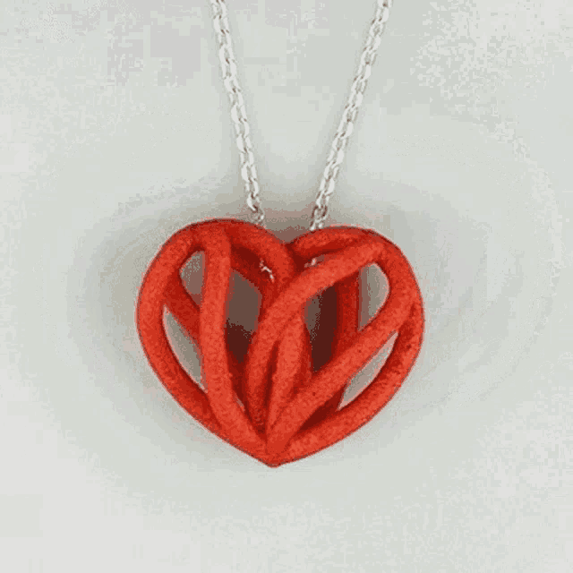 a necklace with a red heart shaped pendant is on a chain