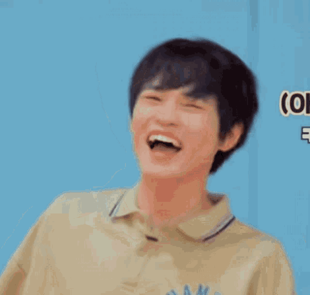 a young man wearing a yellow polo shirt is smiling and laughing .