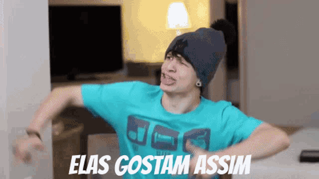 a man wearing a beanie and a blue shirt that says elas gostam assim