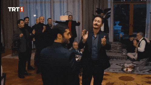 a group of men are dancing in front of a screen that says trt 1 on it