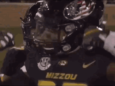 a man is kneeling down in front of a football helmet .