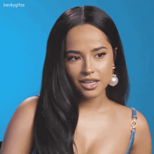 a woman wearing a blue tank top and pearl earrings