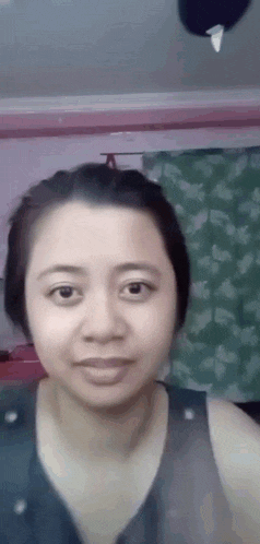 a close up of a woman 's face with a ceiling fan in the background .