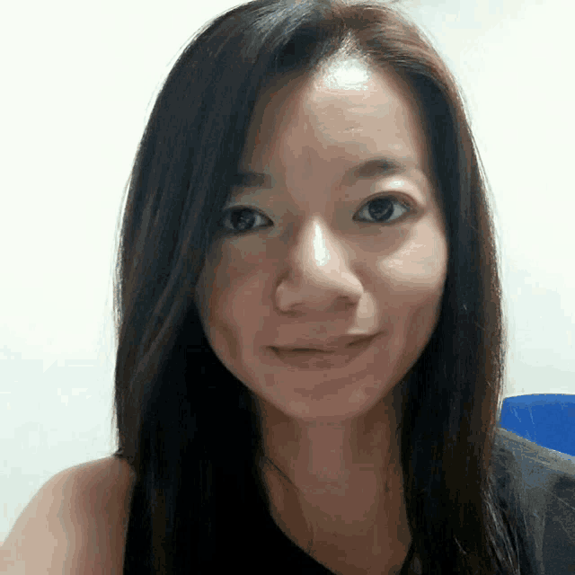 a woman with long dark hair is smiling and wearing a black tank top