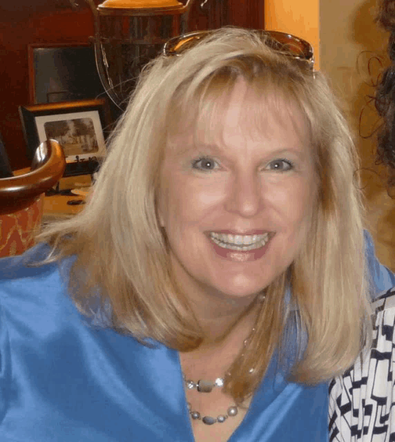 a woman wearing a blue shirt and sunglasses smiles for the camera