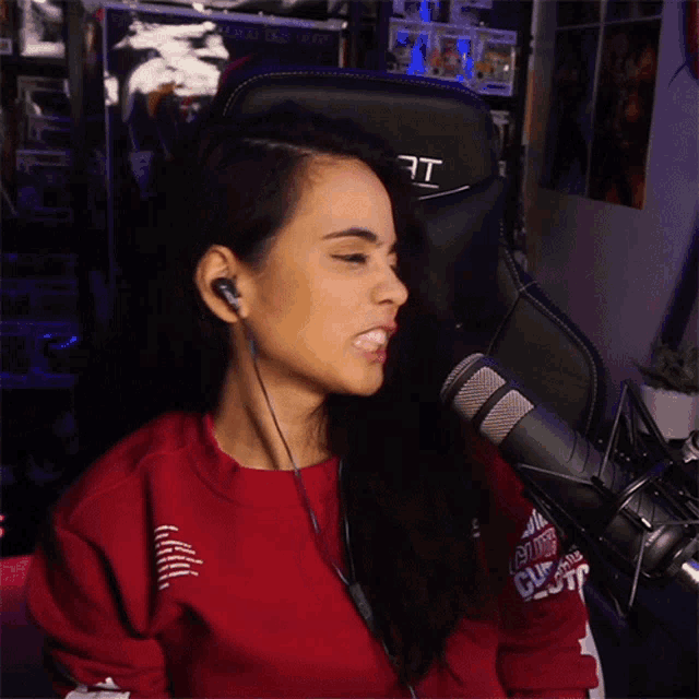 a woman wearing headphones sitting in front of a microphone and a chair that says rt