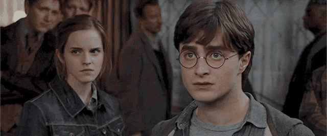harry potter and hermione granger are standing next to each other in a room looking at each other .