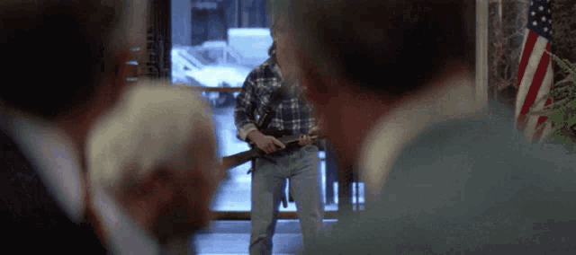 a man in a plaid shirt is standing in front of a group of people