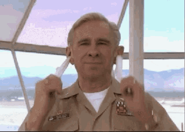 a man in a military uniform is holding a white object in his hand .
