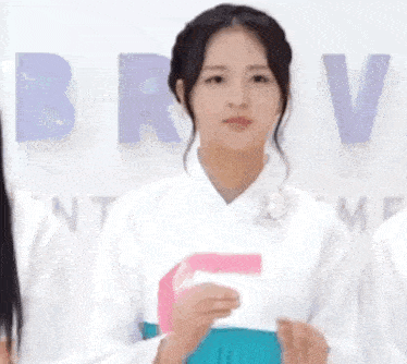 a woman in a white shirt and a blue skirt is standing in front of a wall with letters .