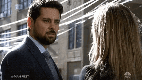 a man in a suit and tie is looking at a woman with the hashtag #manifest on the bottom of the image