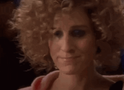 a close up of a woman 's face with curly blonde hair .