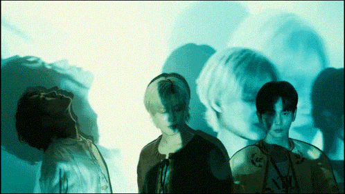 a group of young men are standing in front of a blue background
