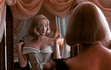 a woman in a white dress is looking at her reflection in a mirror