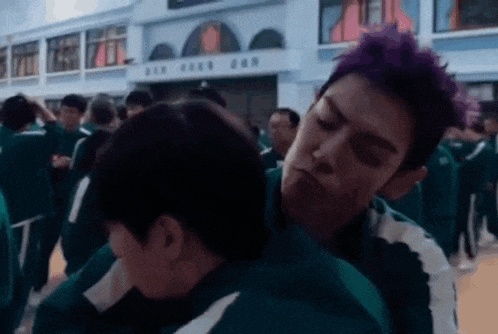 a man with purple hair is standing next to a woman in a crowd of people .