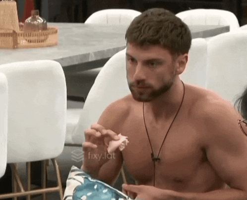 a shirtless man is sitting at a table eating food .