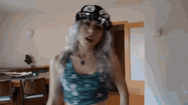 a woman wearing a hat and a crop top is dancing in a room .