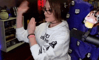 a woman wearing glasses and a choker is sitting in a chair with her arms outstretched .
