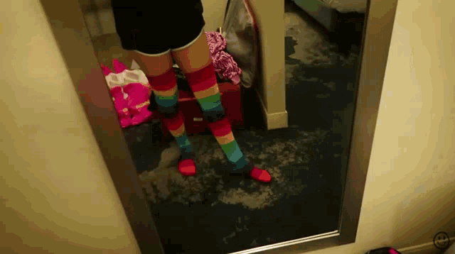 a person standing in front of a mirror wearing rainbow colored socks