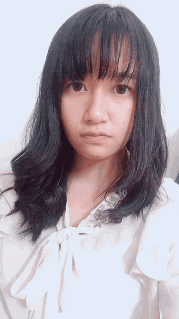 a woman with long black hair and bangs looks at the camera