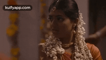 a woman is wearing a garland of flowers in her hair and a necklace .