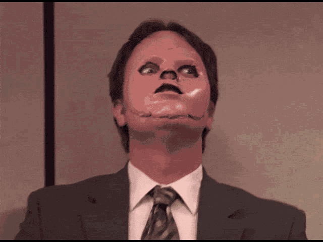a man in a suit and tie is wearing a metal mask