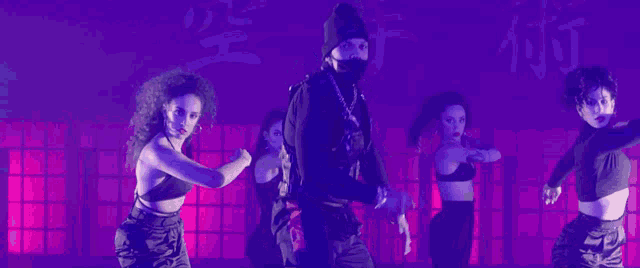 a group of dancers are performing in front of a purple background with chinese characters on it