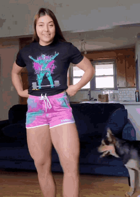 a woman in a black shirt and pink shorts is standing in front of a blue couch