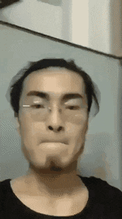 a man wearing glasses and a black shirt is making a face .