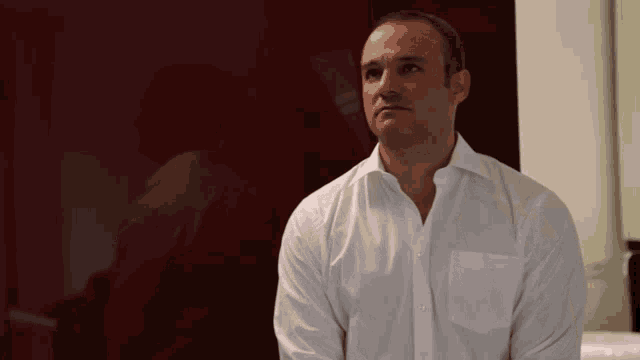 a man in a white shirt is standing in front of a red wall