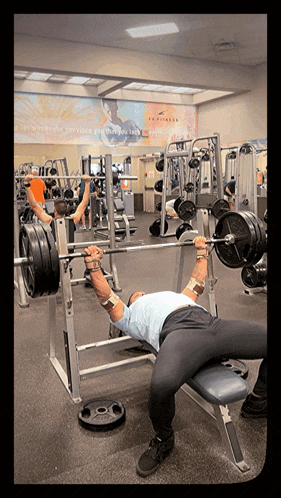 a man lifting a barbell in a gym with a sign that says in fitness