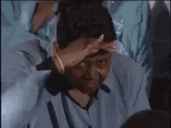 a woman wearing a blue shirt is covering her face with her hand .