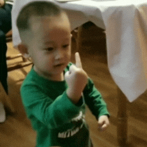 a little boy in a green shirt is giving a thumbs up sign